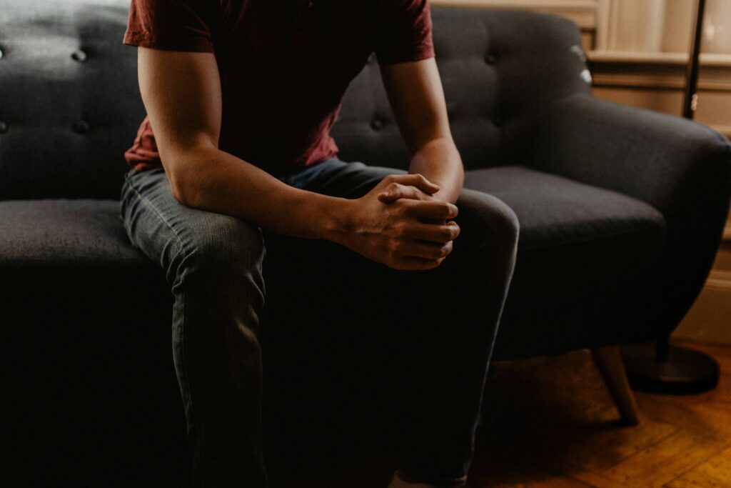 a worried man sitting down rubbing his hands